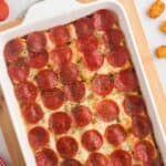 Pinterest image with title overlay for meat-loving pizza tater tot casserole topped with pepperoni slices.