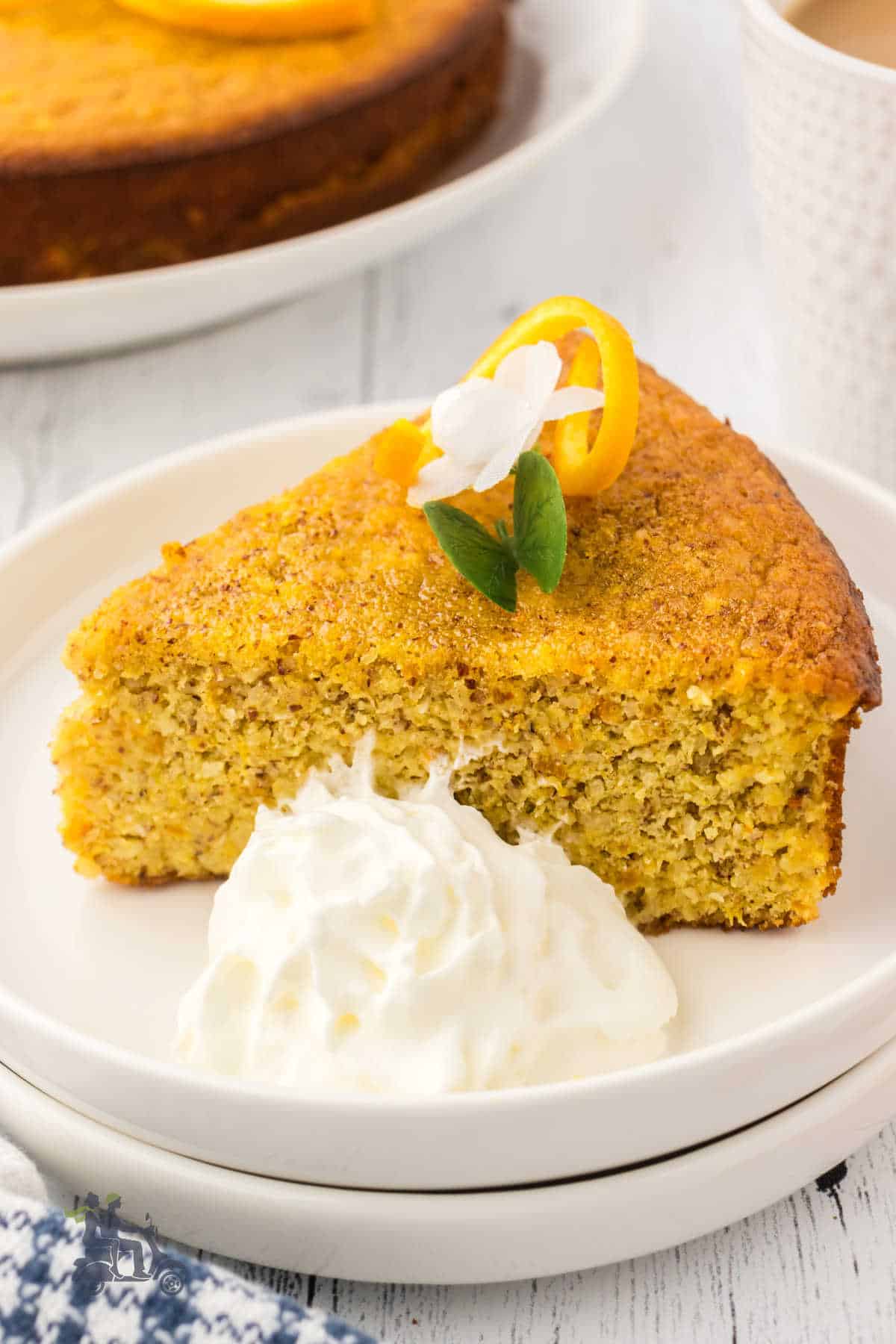 A slice of almond orange cake with whipped cream on the side. 