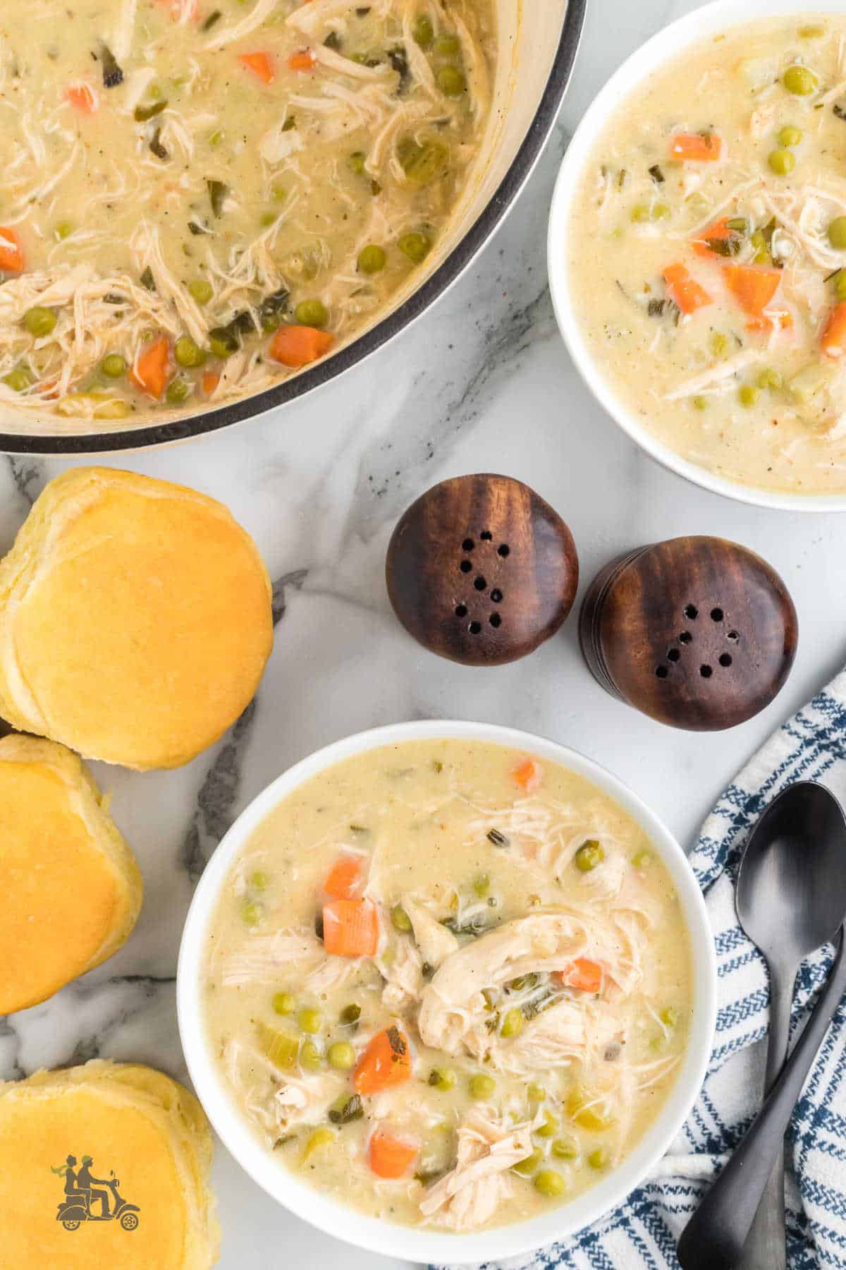 Two soup bowls filled with chicken pot pie soup and homemade biscuits on the side. 