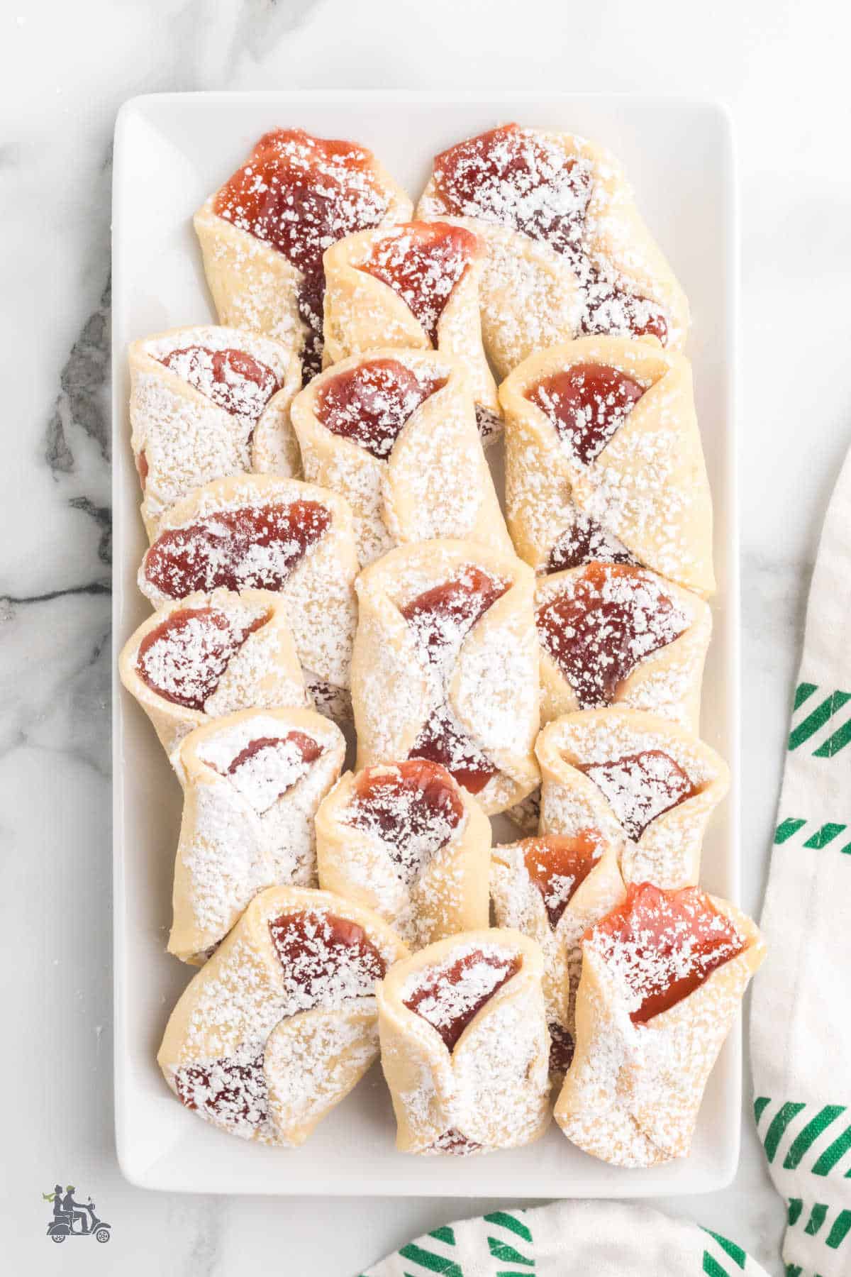 A platter of pinch cookies filled with strawberry jam. 