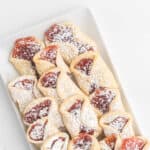 Pinterest image with title overlay of Classic Italian Pizzicati cookies with strawberry jam filling and powdered sugar on top.