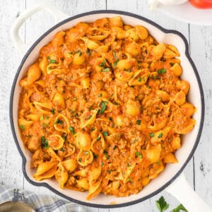 Roasted Red Pepper Sauce made with cream and tossed with shell pasta in a white Dutch Oven.