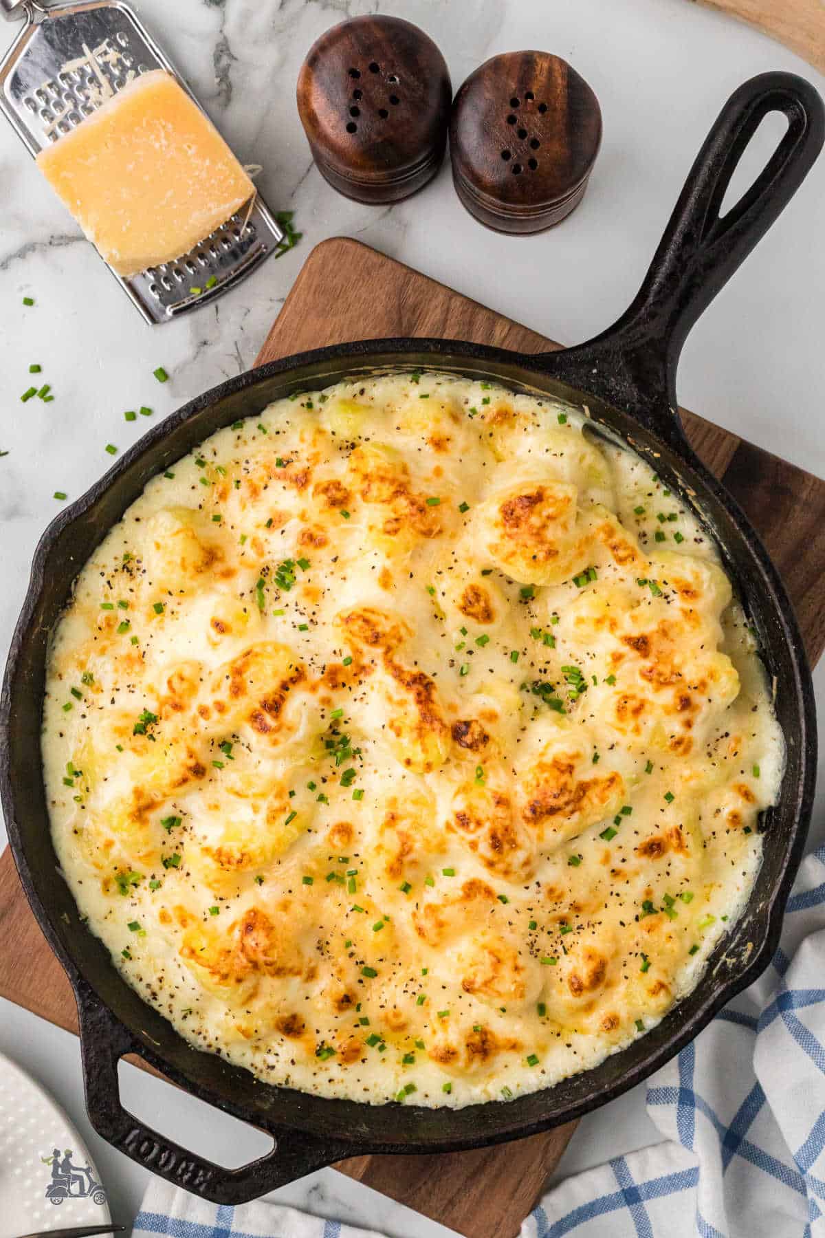 Baked potato gnocchi in a black cast-iron skillet bathed in a rich, creamy Parmesan sauce. 