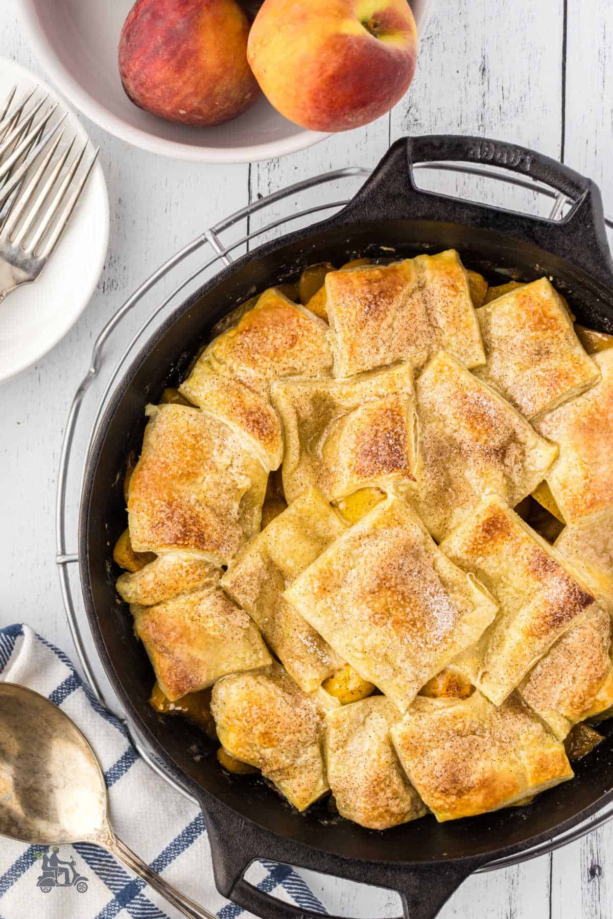 Baked Peach Cobbler with cinnamon sugar sprinkled top in a black cast iron skillet. 