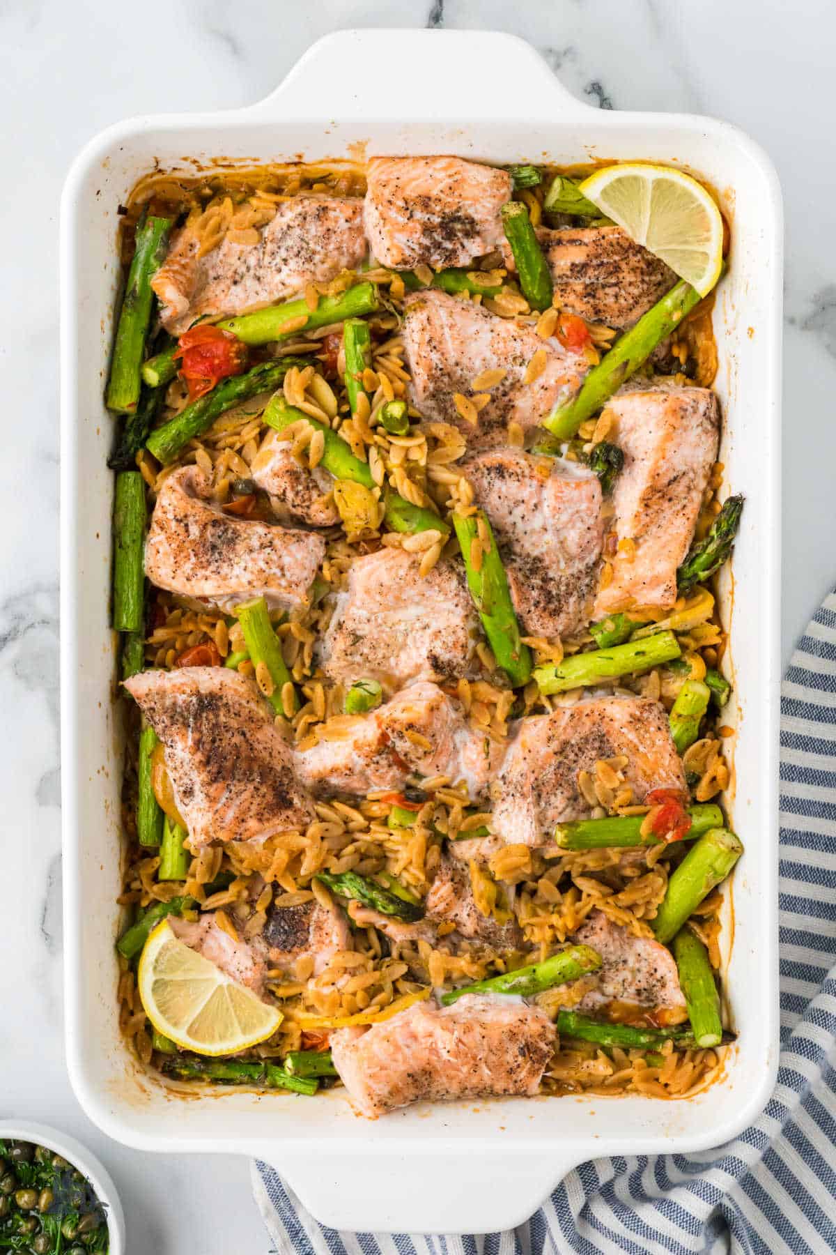 Lemon Salmon and Orzo Casserole recipe in one white baking dish for an easy weeknight dinner. 