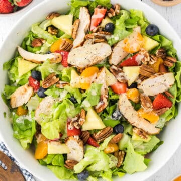 A salad bowl filled with Strawberry Lettuce combination and grilled chicken dressed with poppyseed dressing.