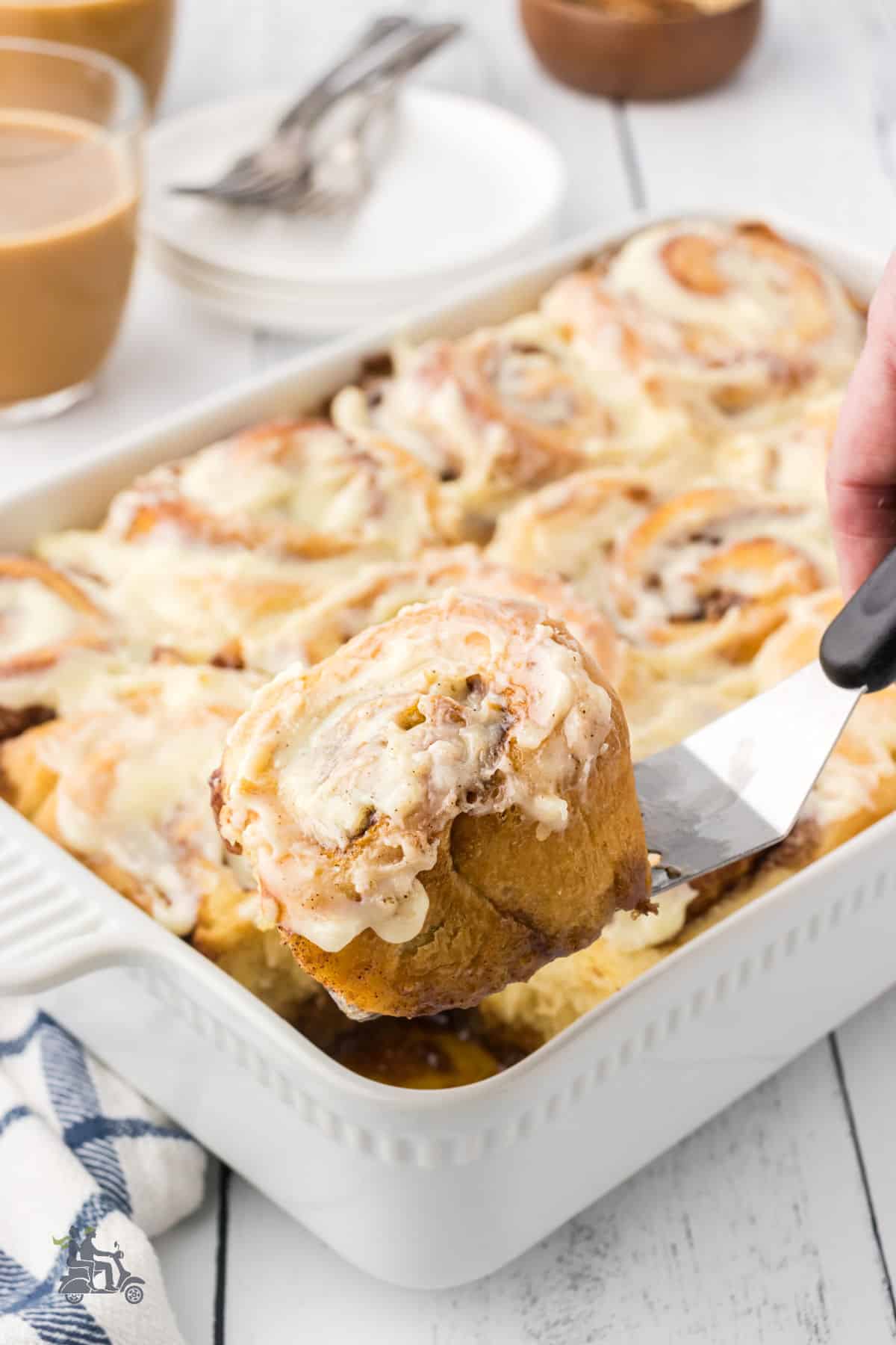 A spatula removes a yeast cinnamon roll from the baking pan. 