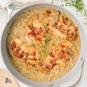 Skillet with Chicken breasts covered in a creamy gravy.