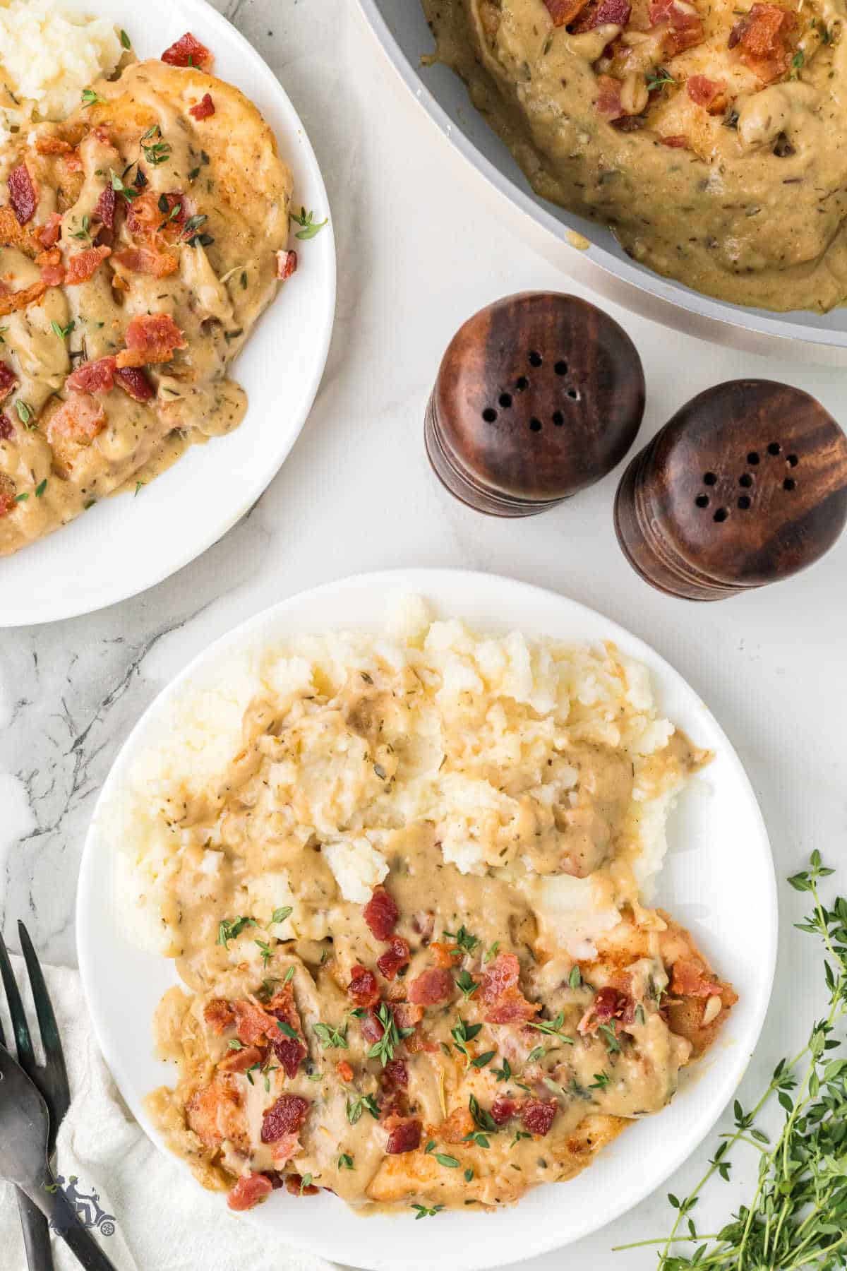 Two plates with a serving of Southern Smothered Chicken recipe presented with creamy mashed potatoes. 