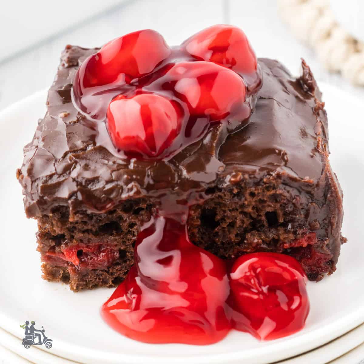 A slice of Chocolate Cake made with cherry pie filling and topped with a chocolate ganache frosting.