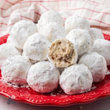 Italian wedding cookies stacked on a red serving plate.