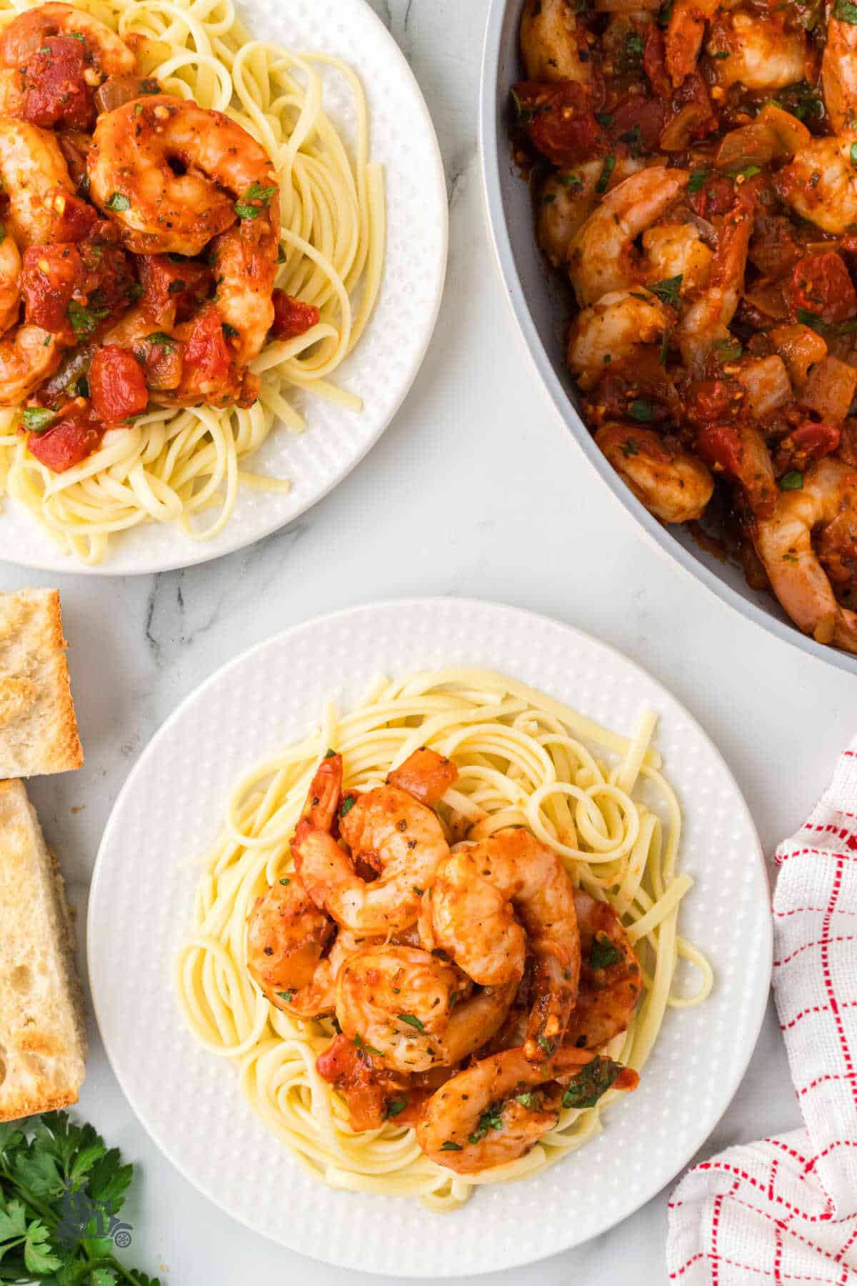 Shrimp Fra Diavolo is served over spaghetti with a preparation skillet on the side. 