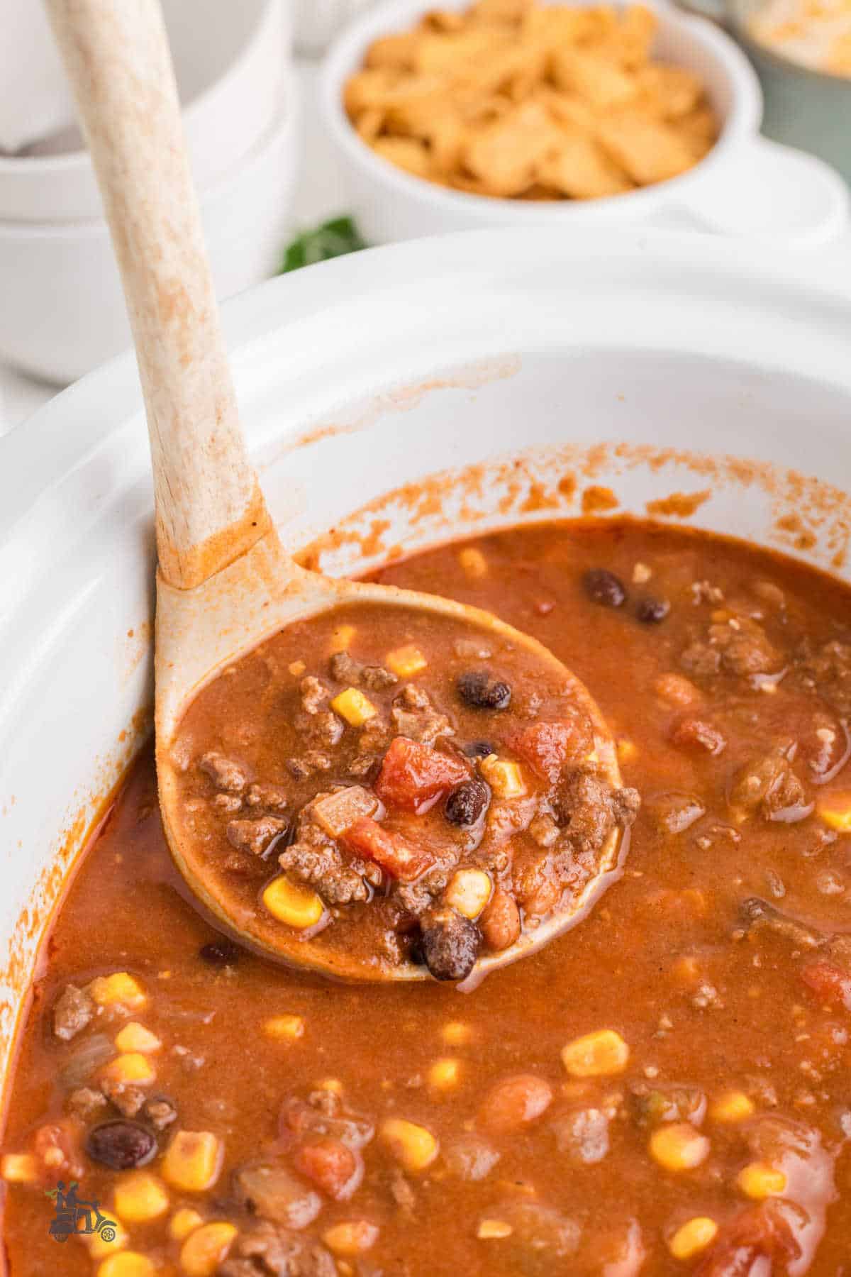 A spoon dips into the slow cooker for a scoopful of taco soup. 