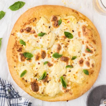 Italian White Pizza made with three cheeses and topped with fresh basil leaves.