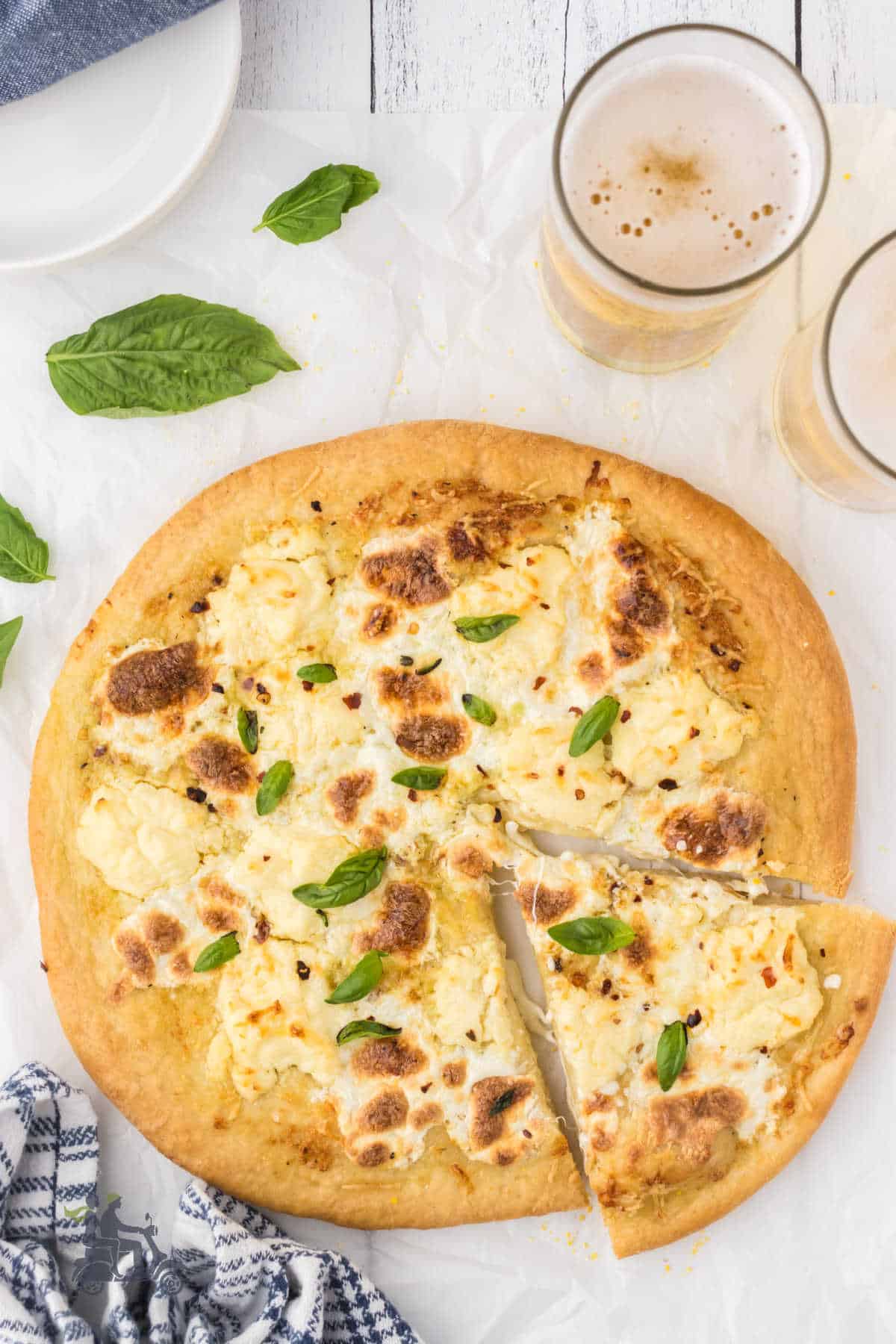 White pizza has three cheeses and a slice cut into the round pie. 