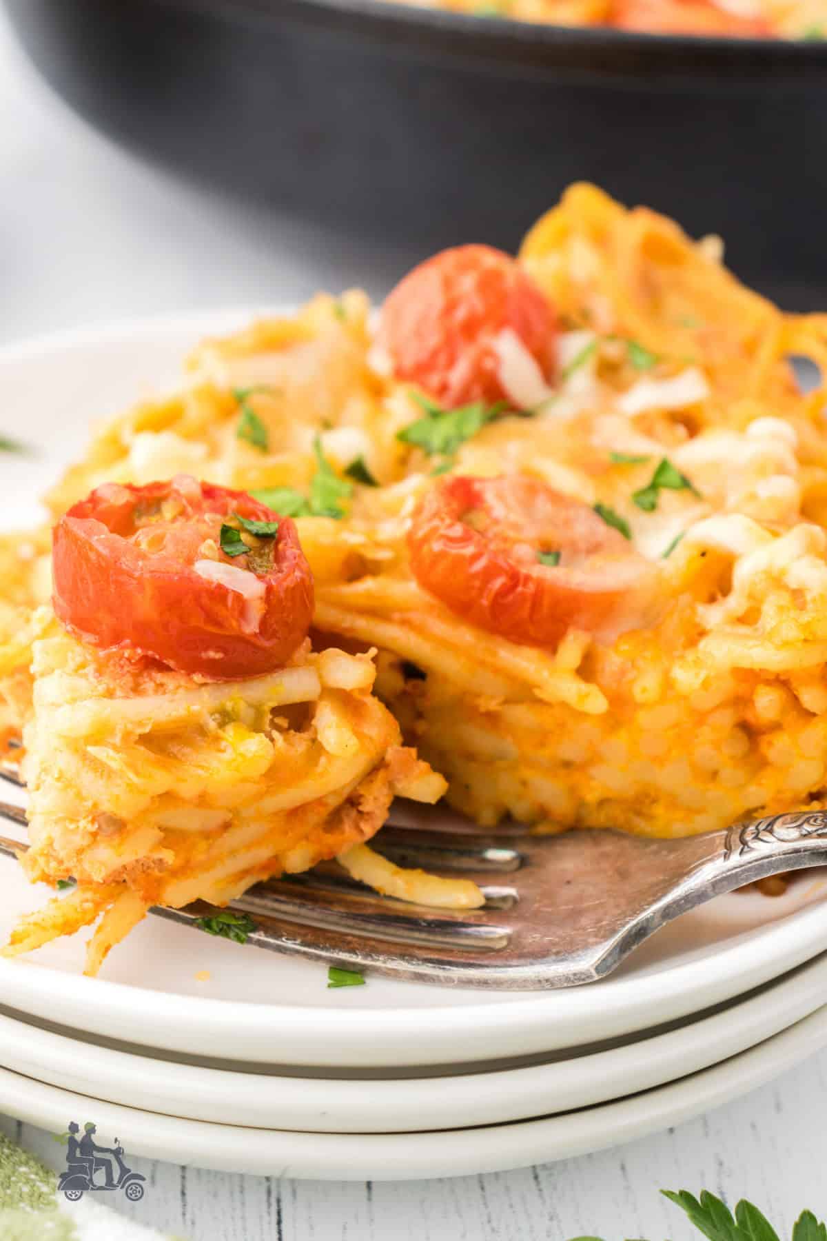 Side view of a spaghetti frittata wedge with a forkful removed. 