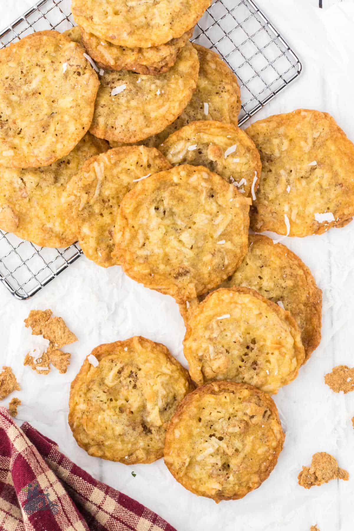 Shredded coconut cookies on a cooling rack with more on the white counter. 