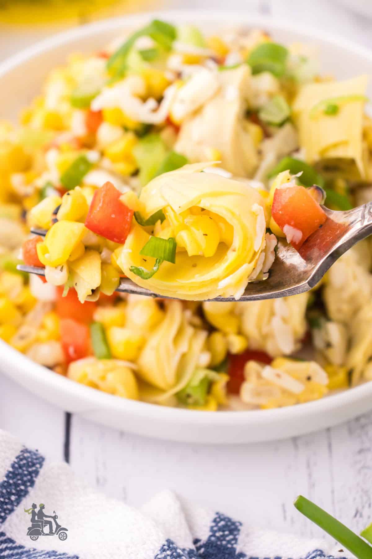 A fork holds up a bite of the Italian summer salad made with corn and artichokes. 