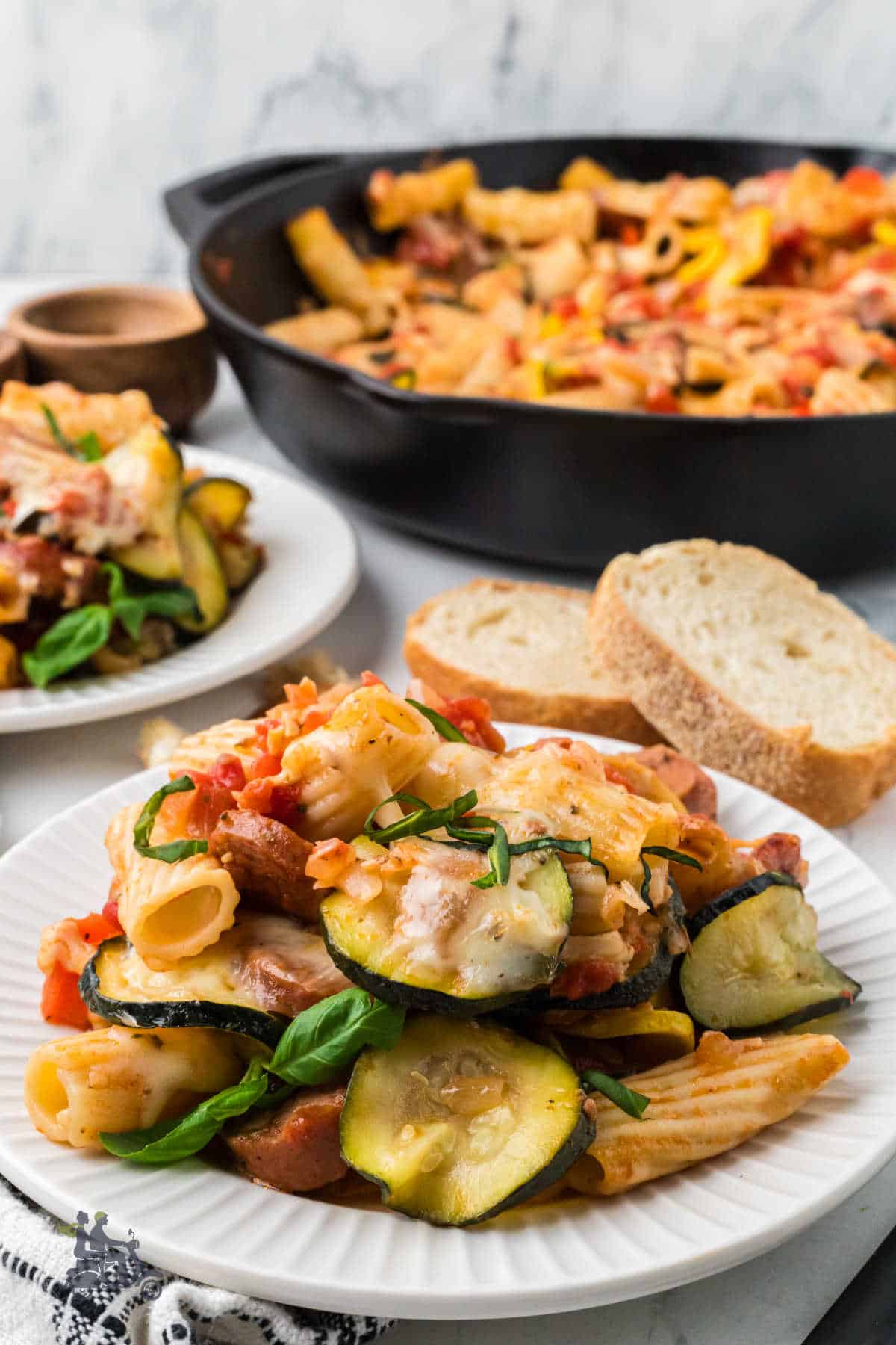 A serving of sauteed summer vegetables with melted cheese on a white plate. 