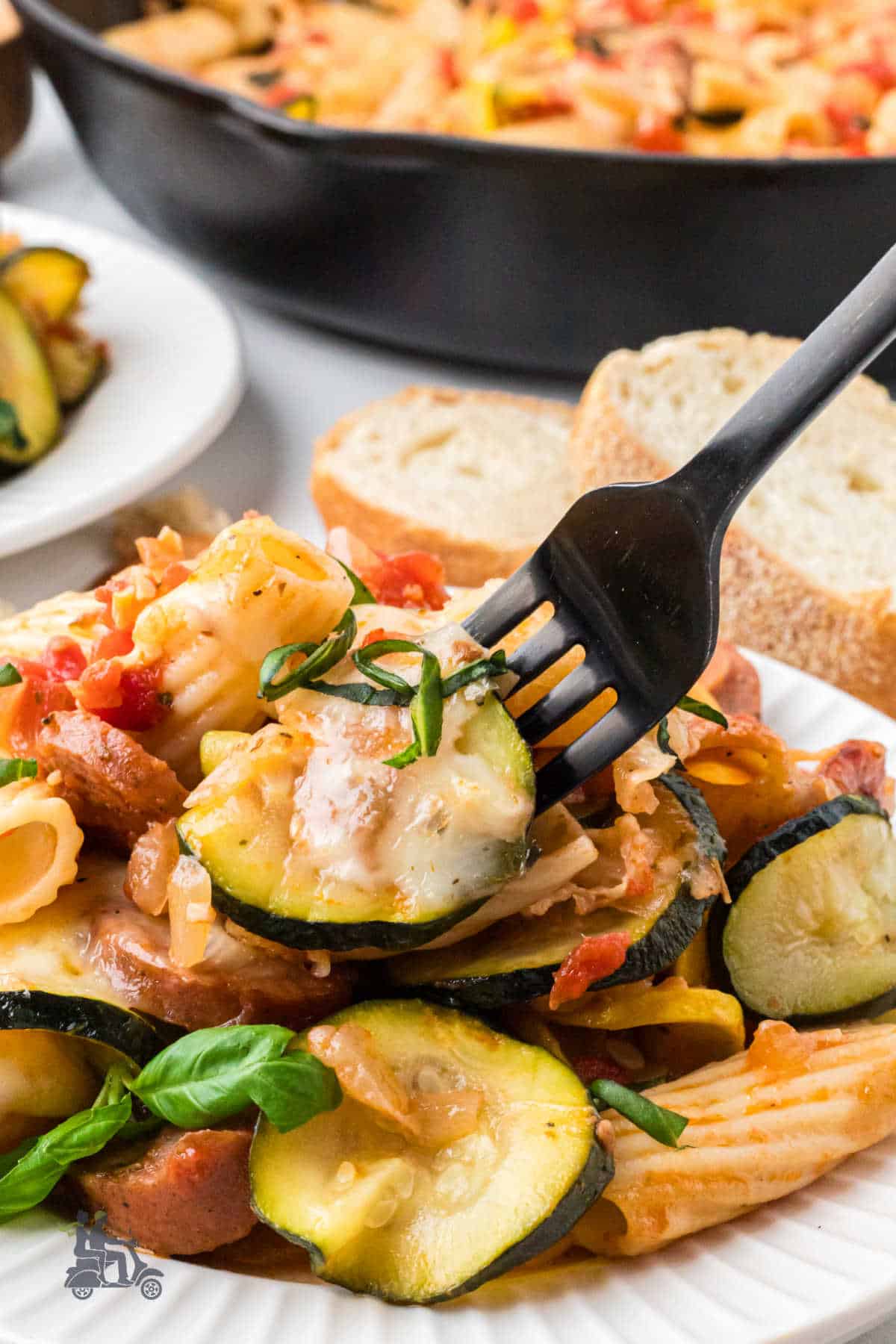 A fork is piercing a cooked zucchini round from the Pasta Estiva dish. 