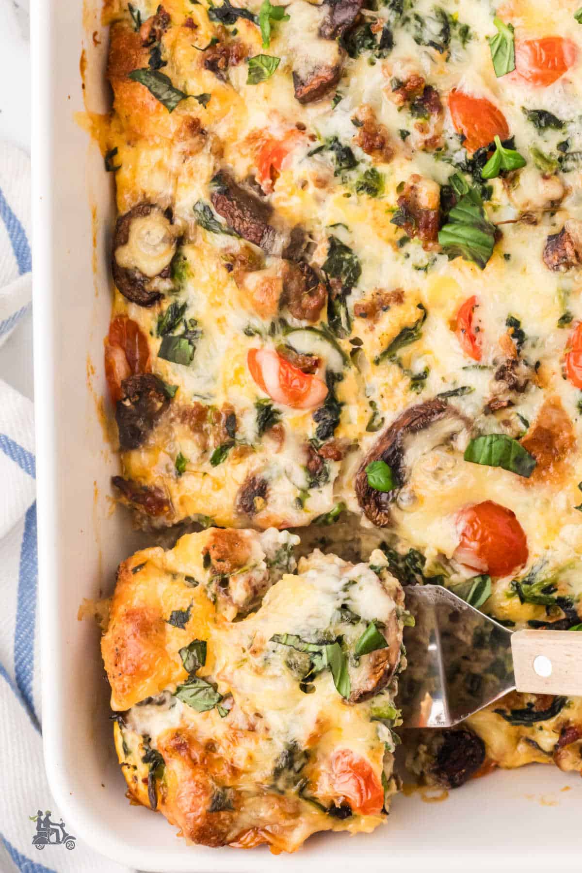 A spatula removes a square of the breakfast strata from the casserole dish. 