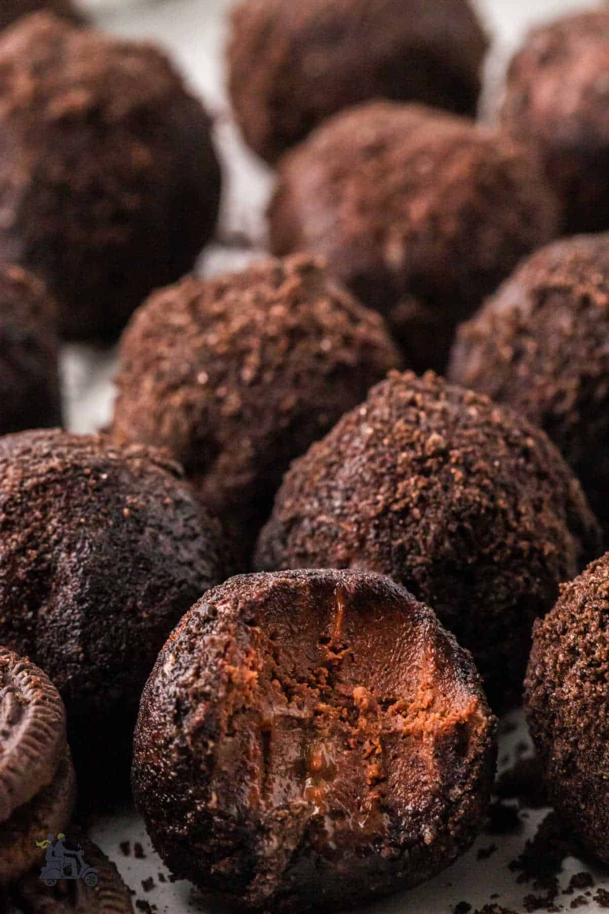 A rum ball rolled in crushed chocolate crumbs with a bite taken out of it. 