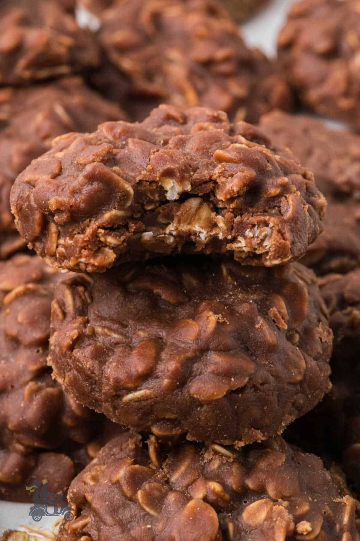 Oatmeal Chocolate no-bake cookies stacked with a bite taken from the top cookies. 