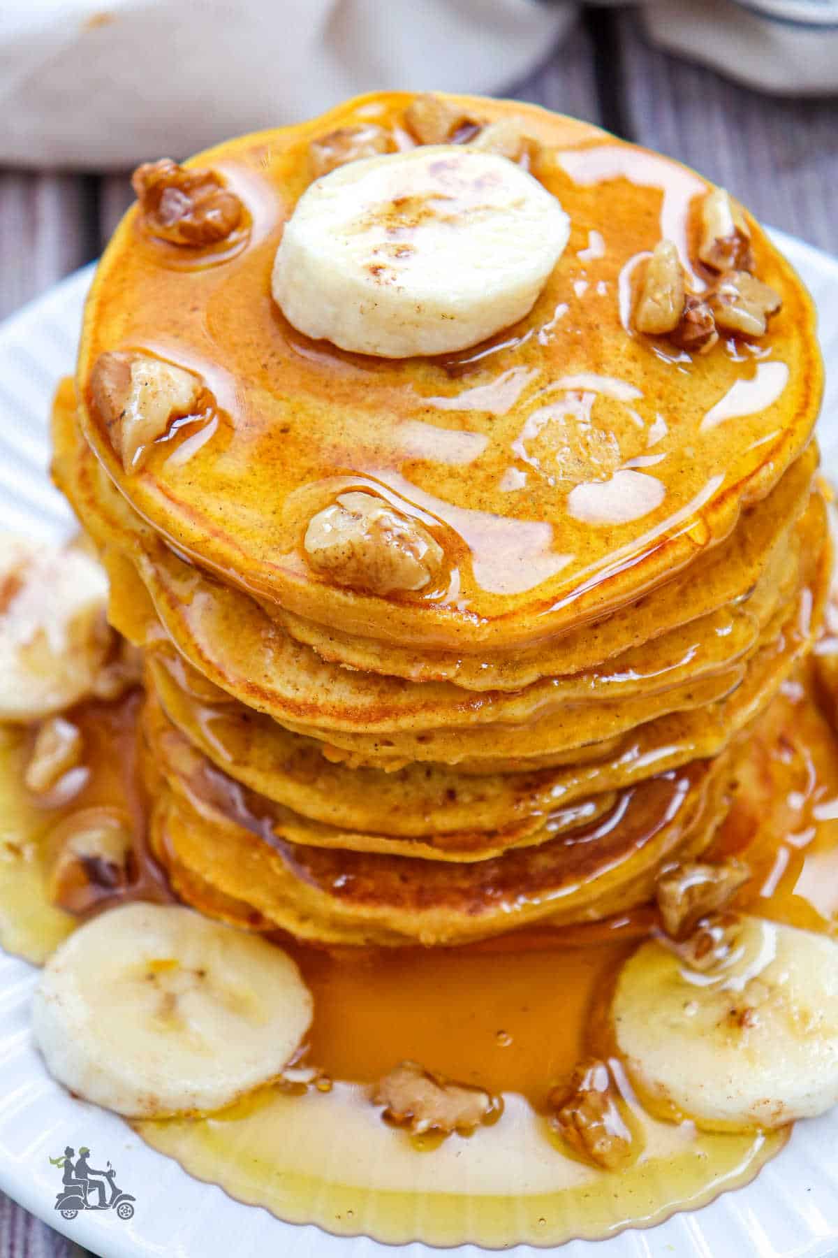 A tower of breakfast pancakes made with pumpkin and bananas topped with maple syrup. 