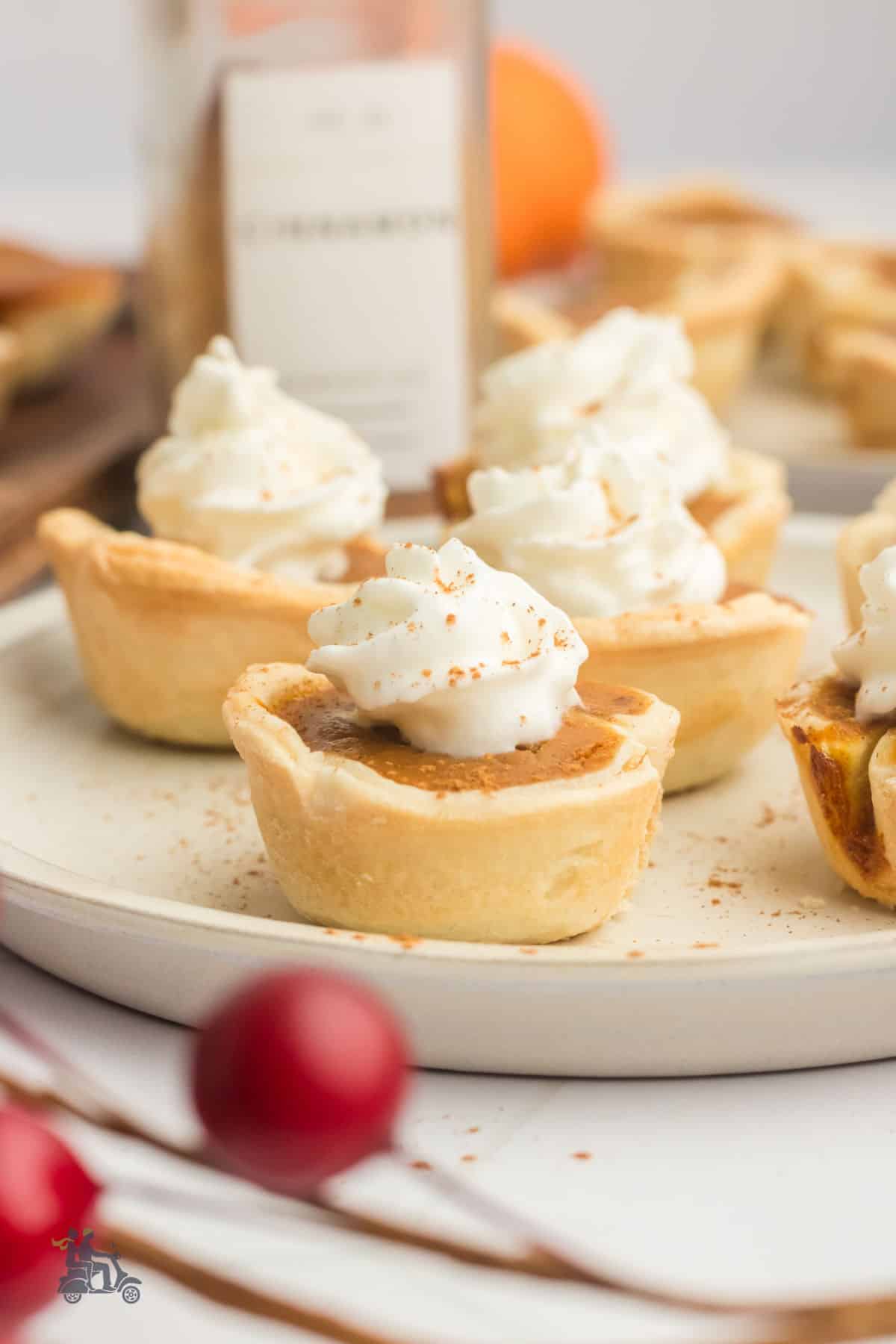 Mini pumpkin pies topped with dollops of whipped cream and a sprinkle of ground cinnamon. 