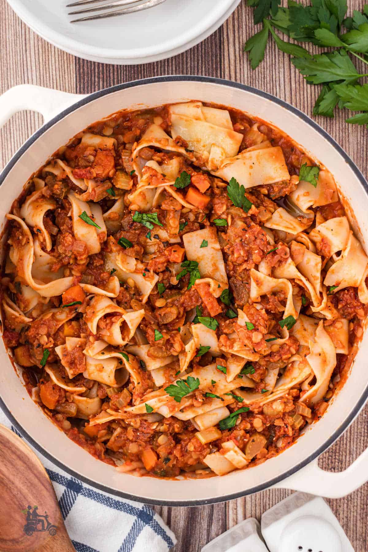 A large, deep skillet filled with hearty lentil bolognese tossed with flat, broad pappardelle pasta. 