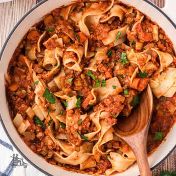 Lentil pasta sauce made into a vegetarian bolognese ragù in a large skillet mixed with pappardelle noodles.