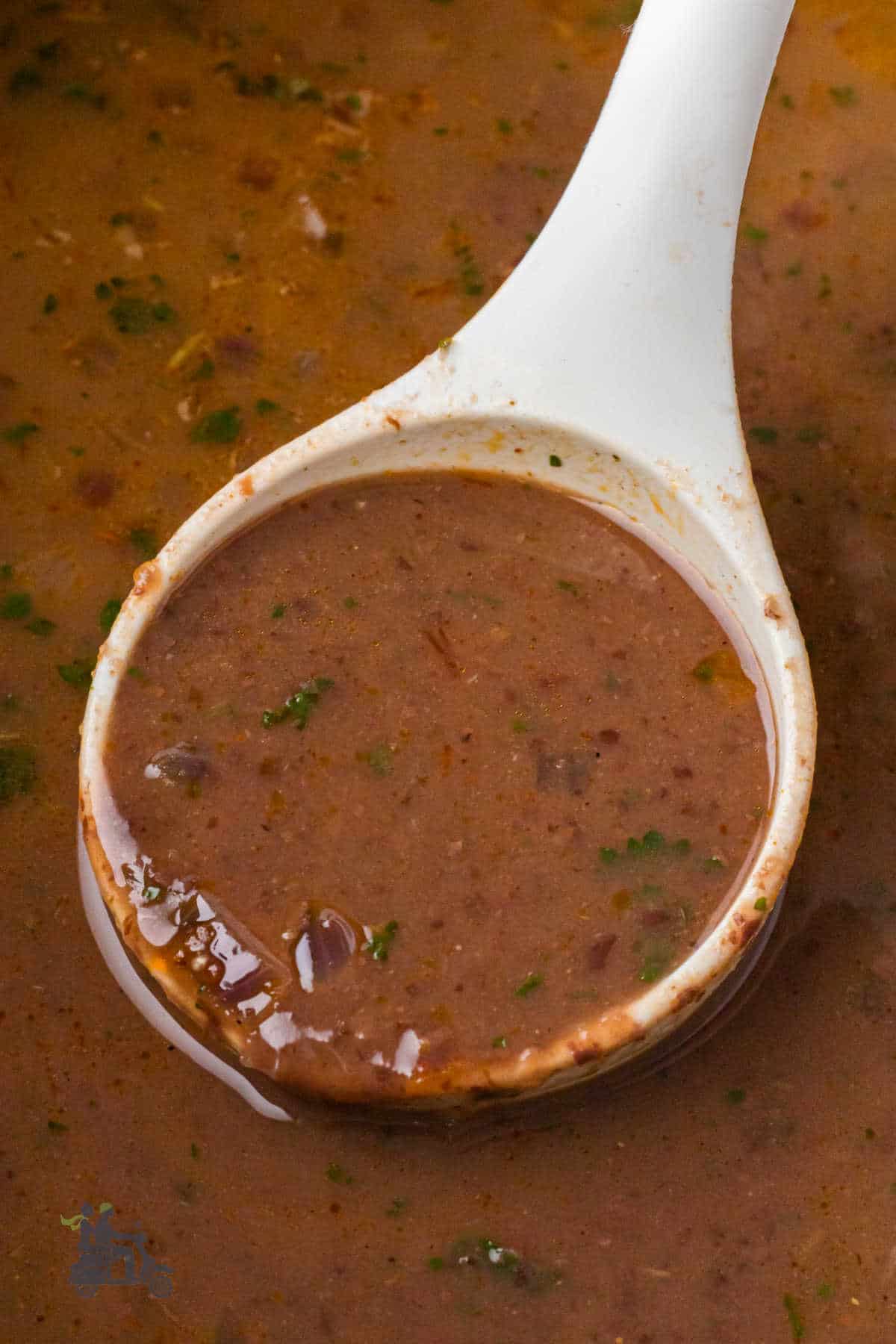 A soup spoon holds a scoop of creamy soup made with black beans. 