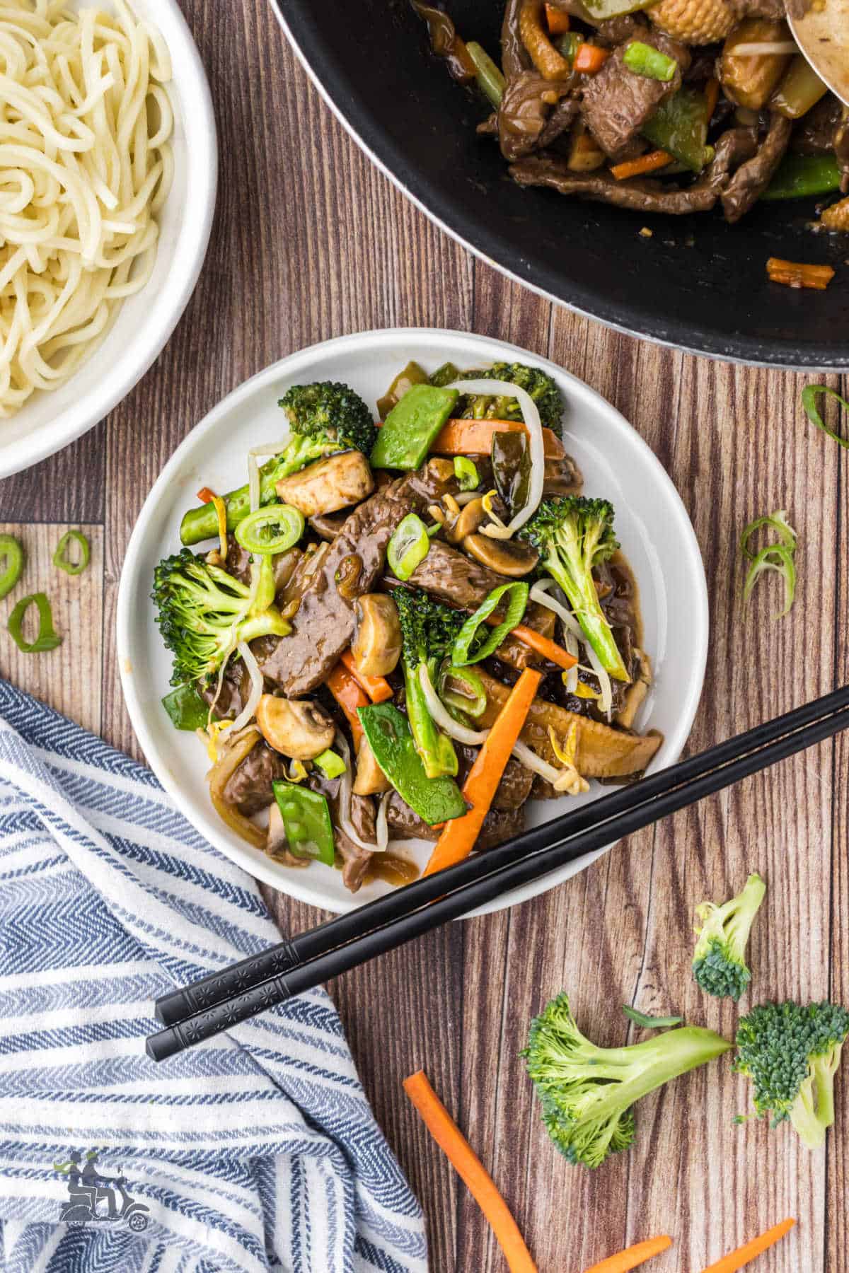 A white plate holds a serving of Beef Chop Suey with chopsticks positioned on the side of the plate.