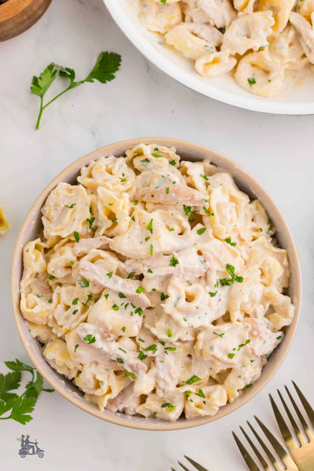 A white serving bowl filled with creamy Alfredo for chicken dinner. 