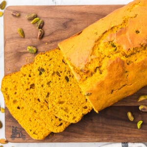 Savory pumpkin loaf on a cutting board with slices cut from it.