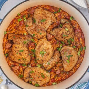 A deep pot filled with Cajun-flavored chicken thighs with creamy orzo pasta.