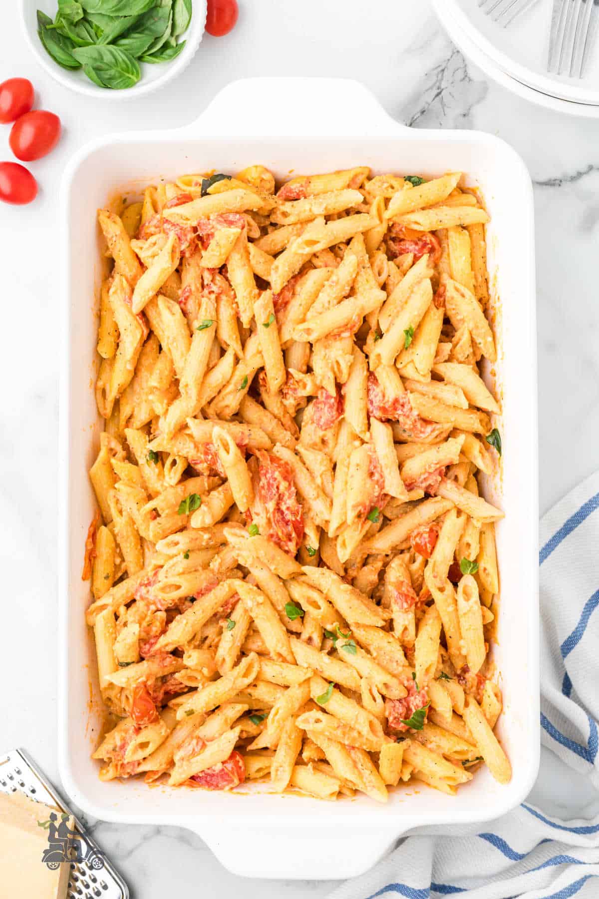 An oblong baking dish holds penne pasta made with Boursin Herb cheese with grape tomatoes. 