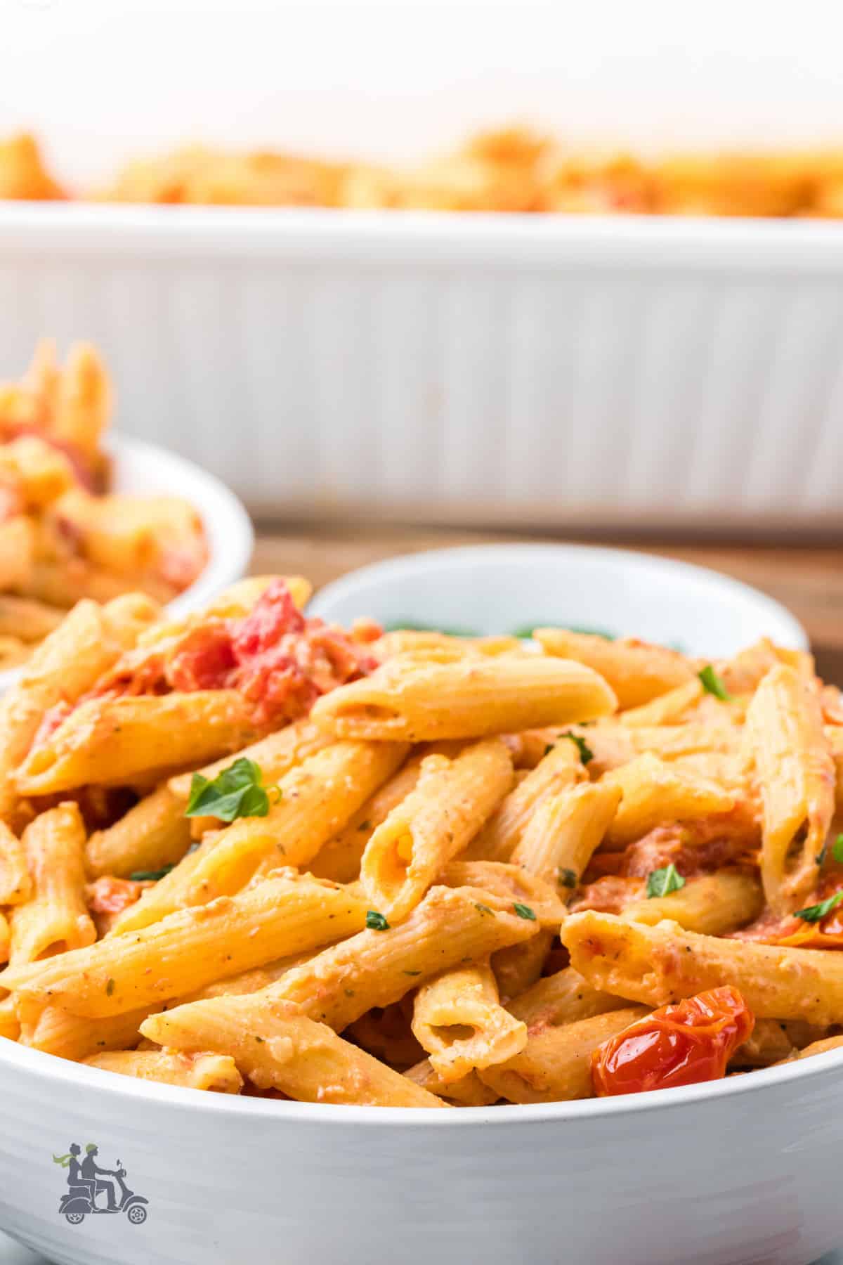 A white pasta bowl holds a serving of penne pasta tossed with a cheese sauce made with grape tomatoes and Boursin cheese. 