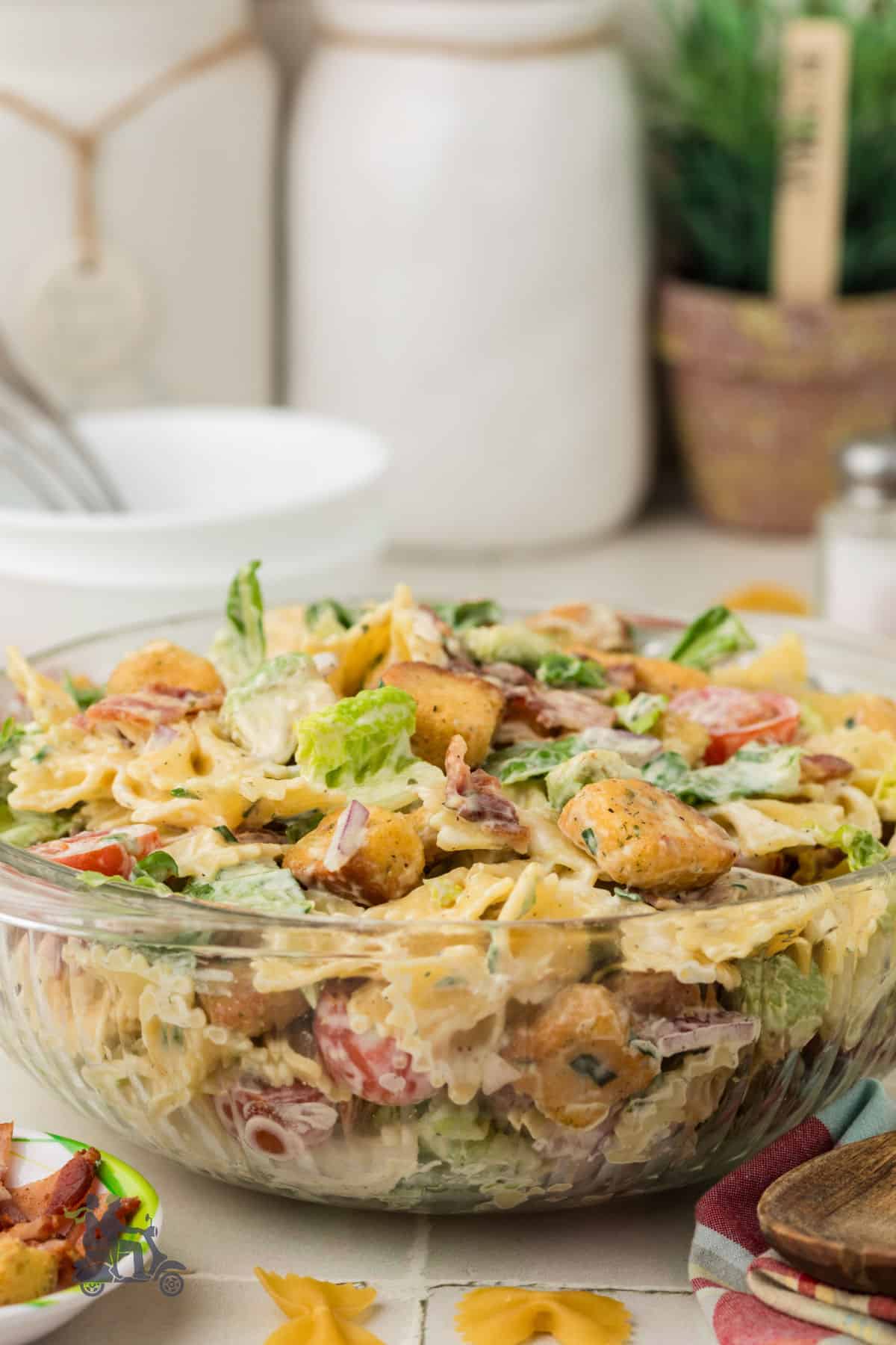 Creamy BLT pasta salad with bowtie pasta, crispy bacon, and chopped romaine in a white bowl.