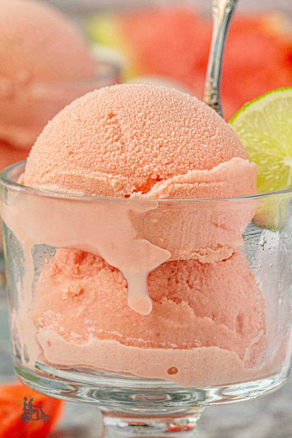 A side view of the frozen watermelon dessert with the creamy sweet melting down the side of the glass.