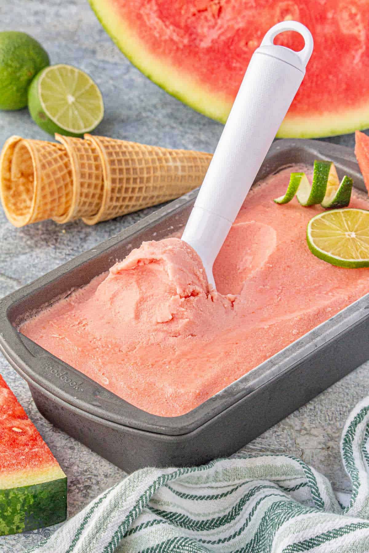 Pink, refreshing watermelon ice cream in a loaf pan with an ice cream scoop.