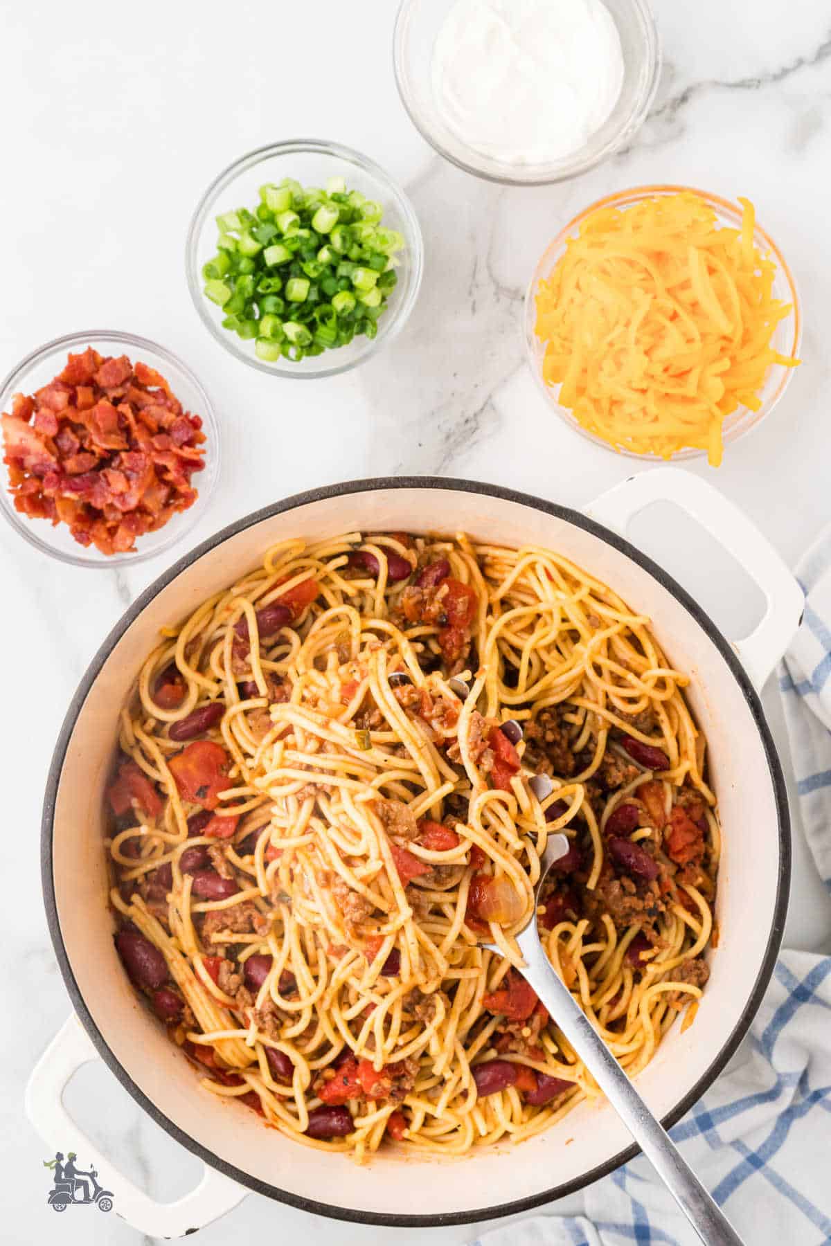 Cowboy spaghetti in a Dutch Oven with garnishes on the side.
