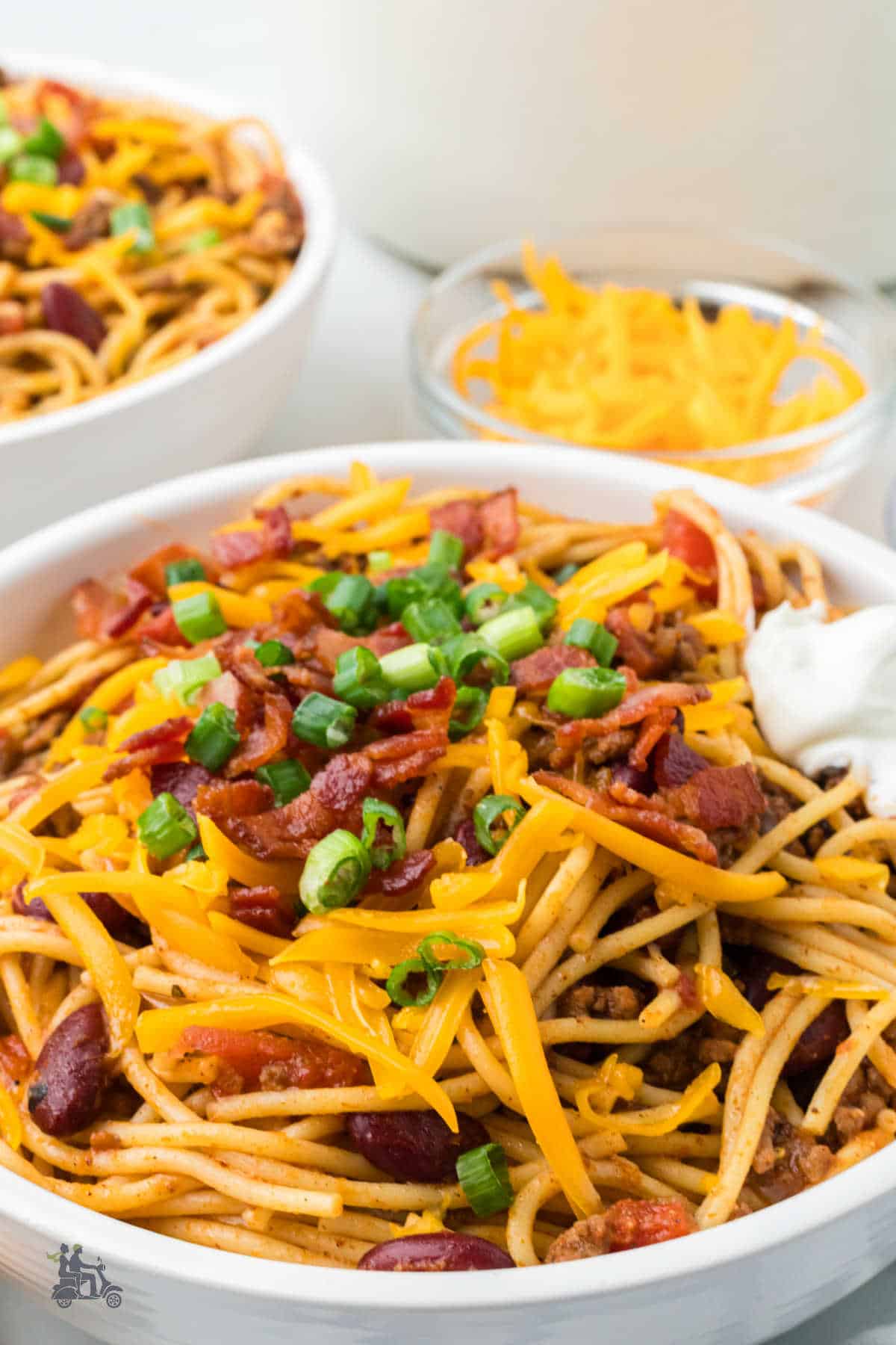 Close-up of Cowboy Spaghetti topped with crispy bacon, sour cream, and green onions.