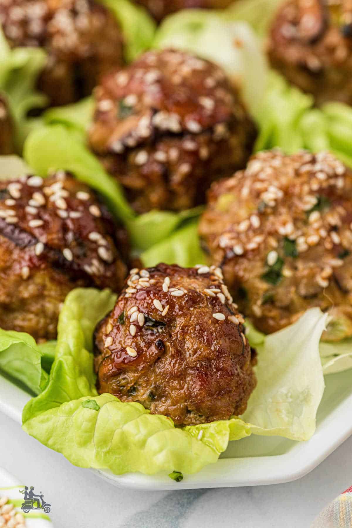Closeup of the savory pork meatballs glazed with homemade Asian sauce served on butter lettuce cups. 