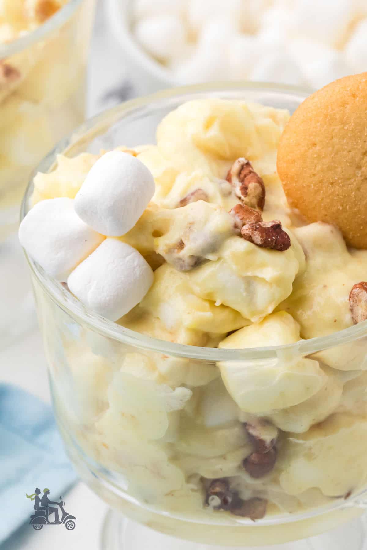Banana pudding mousse with whipped cream in a glass goblet with a vanilla wafer and extra marshmallows on top. 