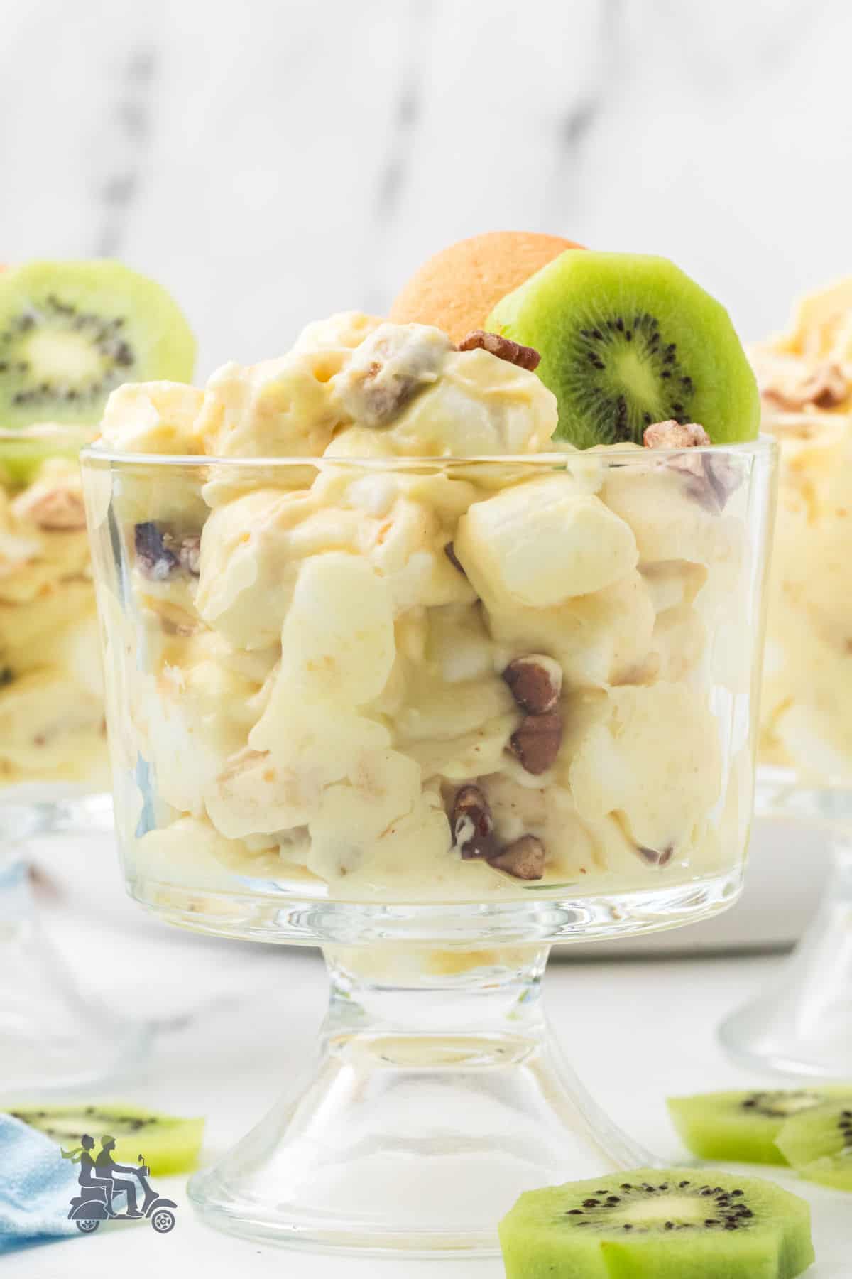 Creamy banana pudding fluff dessert recipe garnished with a kiwi slice and a vanilla wafer. 