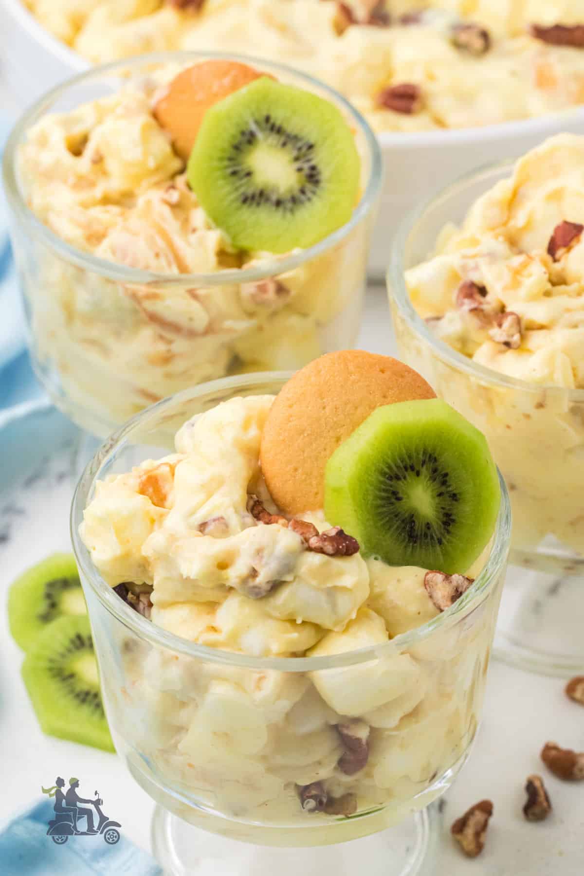 Easy banana pudding fluff with Nilla wafers in glass goblets, garnished with a vanilla wafer and a kiwi slice. 