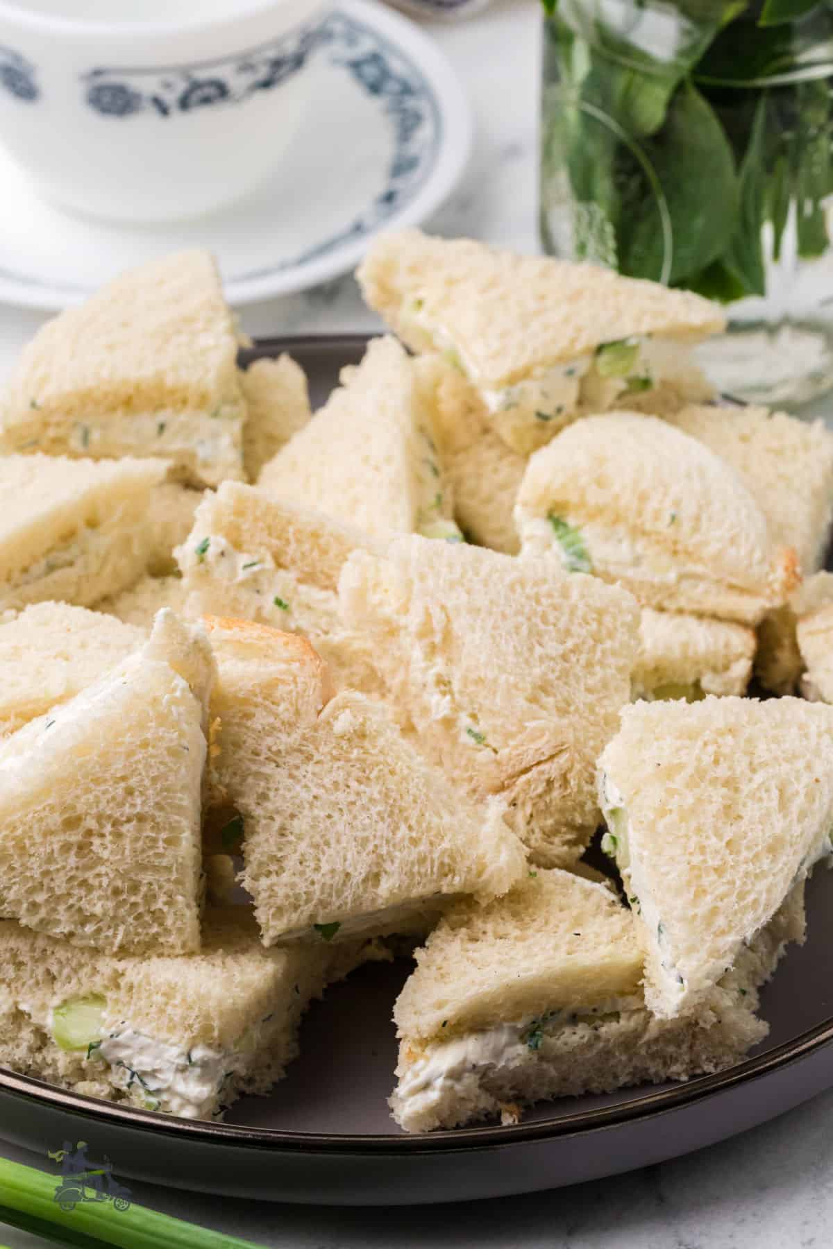 Cool and creamy cucumber sandwiches piled on a brown serving plate.