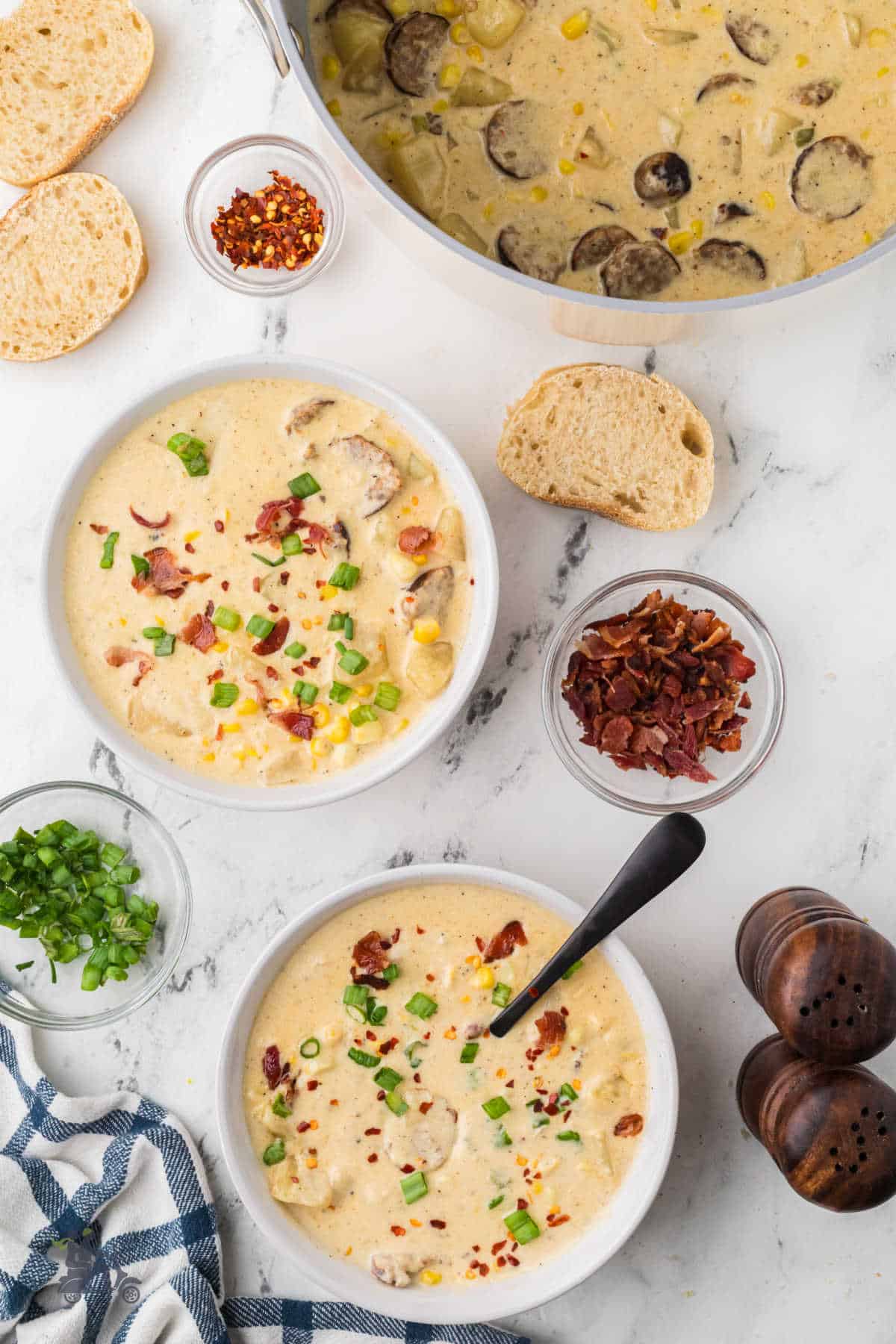 Two rustic bowls of corn and potato chowder with jalapeños in a creamy broth. 