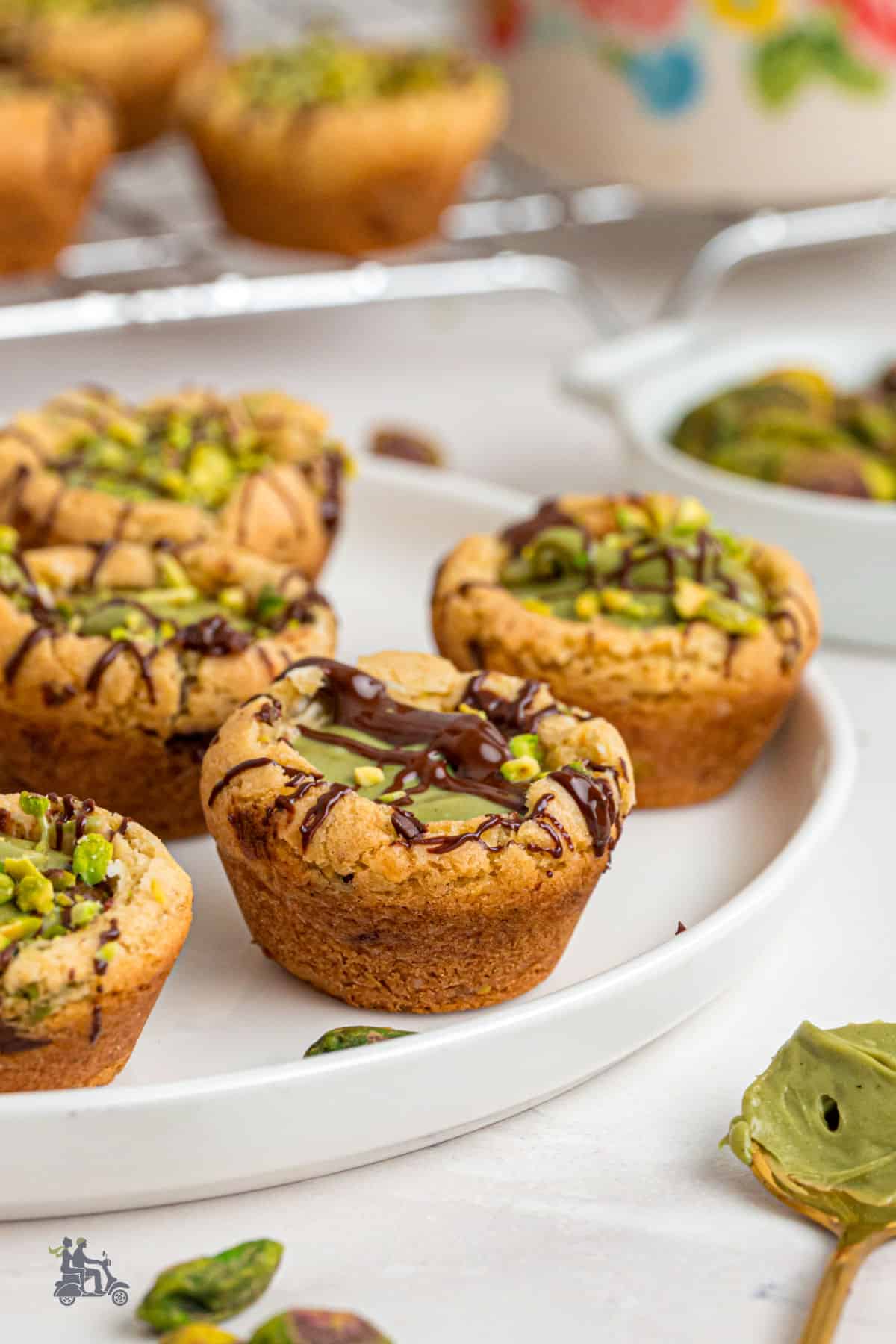 Pistachio cream-filled white chocolate chip cookie cups, drizzled with dark chocolate. 